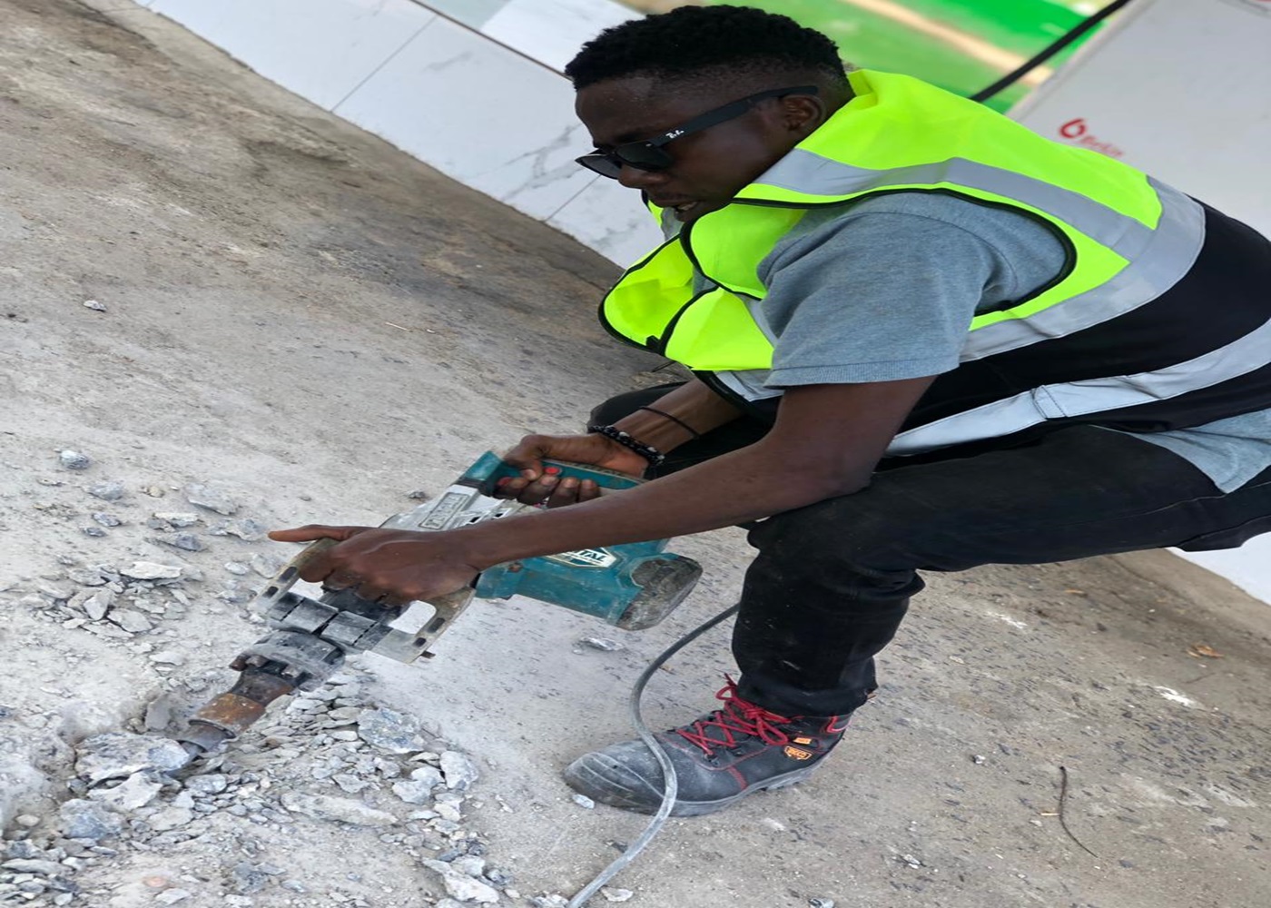 Engineer using a concrete breaker to install conduit at a forecourt