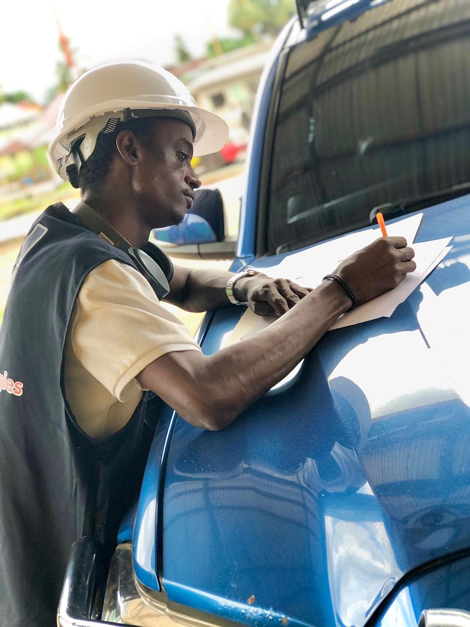 Engineer in hard hat doing a site survey resting paper on a truck hood